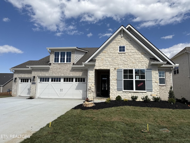 craftsman inspired home featuring a garage, driveway, stone siding, and a front lawn