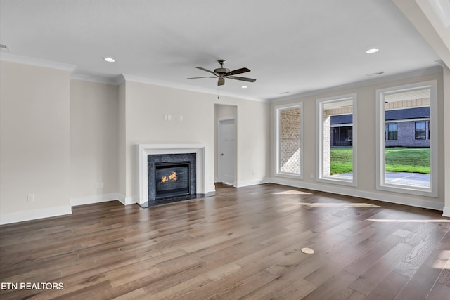 unfurnished living room featuring ceiling fan, a premium fireplace, wood finished floors, and baseboards