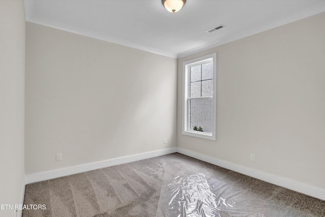 carpeted spare room featuring baseboards, ornamental molding, and visible vents
