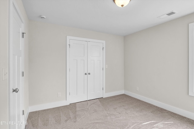 unfurnished bedroom with visible vents, baseboards, a closet, and carpet floors