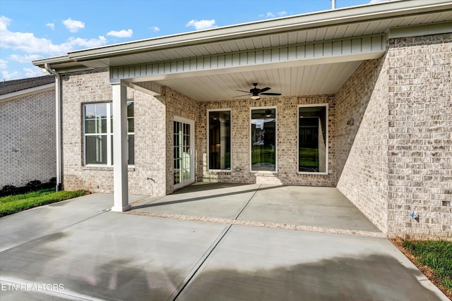 entrance to property with a patio area, brick siding, and a ceiling fan