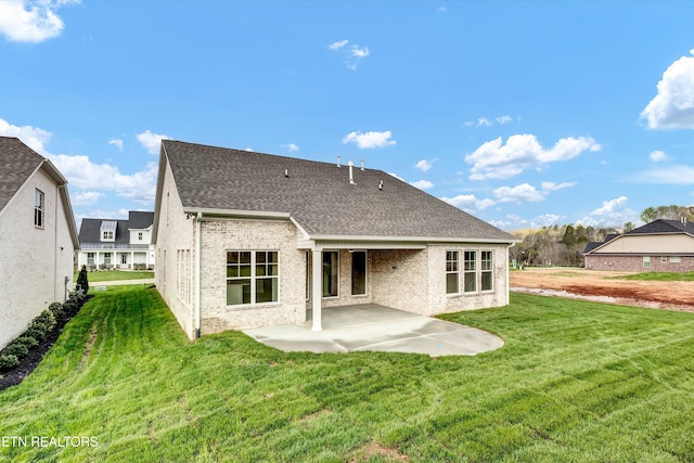 rear view of property with a patio area, a shingled roof, brick siding, and a lawn