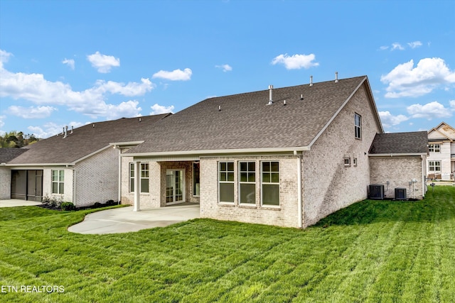 rear view of house featuring central AC unit, a patio, a lawn, and roof with shingles