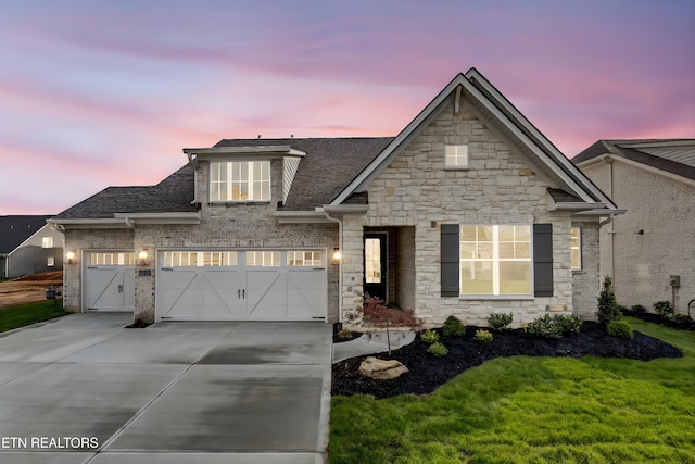 view of front facade with driveway, stone siding, a shingled roof, and a front lawn