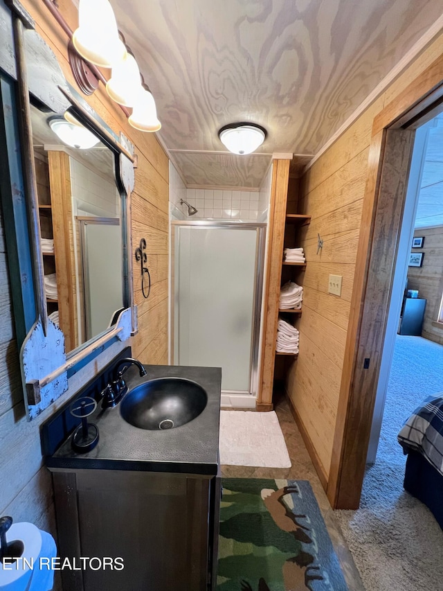 bathroom with vanity, a shower with shower door, and wood walls