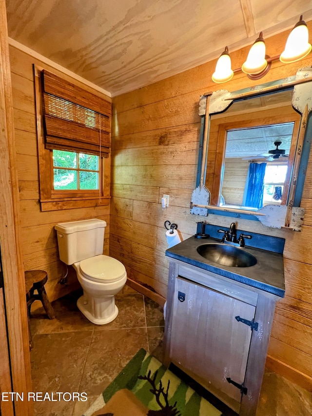 bathroom featuring vanity, toilet, a healthy amount of sunlight, and wood walls