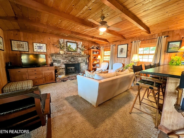 carpeted living room with beam ceiling, ceiling fan, wooden ceiling, and wood walls