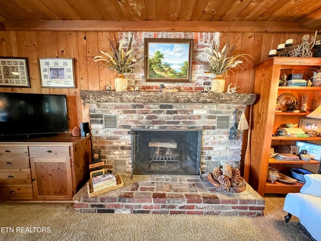 living room featuring beam ceiling, carpet flooring, wooden ceiling, wood walls, and a fireplace