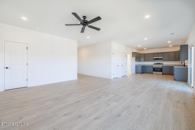 unfurnished living room featuring ceiling fan, sink, and light hardwood / wood-style flooring