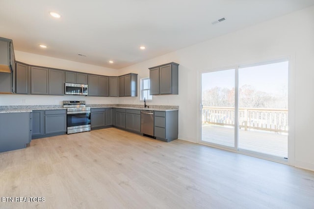 kitchen with gray cabinets, light hardwood / wood-style floors, sink, and appliances with stainless steel finishes