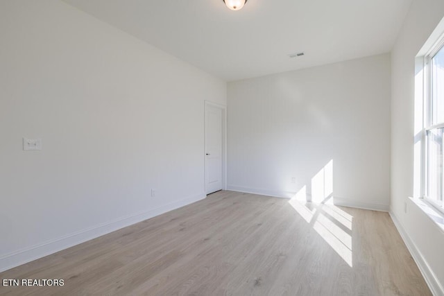 empty room with a wealth of natural light and light hardwood / wood-style flooring