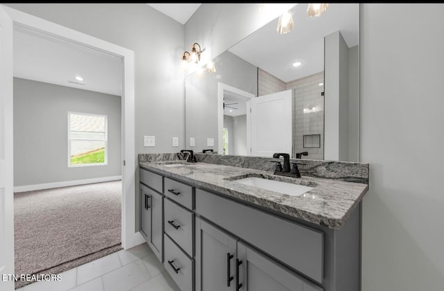 bathroom featuring tile patterned flooring, a tile shower, vanity, and ceiling fan