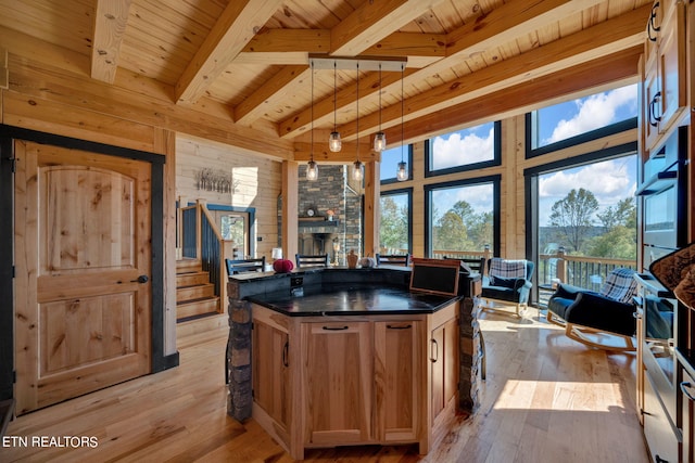 kitchen featuring pendant lighting, beamed ceiling, a kitchen island, wooden ceiling, and light hardwood / wood-style floors