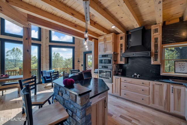 kitchen featuring beamed ceiling, custom exhaust hood, stainless steel double oven, and plenty of natural light