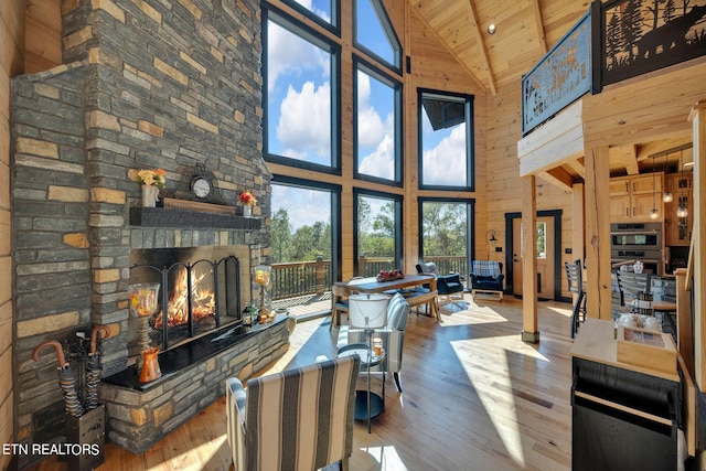 living room with high vaulted ceiling, wooden walls, wood-type flooring, wooden ceiling, and a fireplace