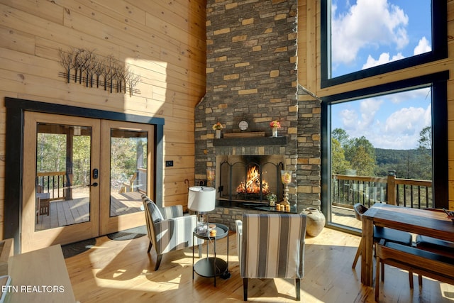 interior space with a towering ceiling, french doors, light hardwood / wood-style floors, and a stone fireplace