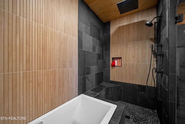 bathroom with tile walls, sink, and tiled shower