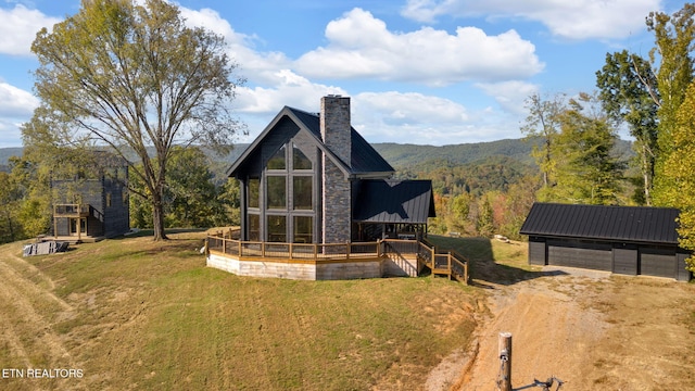 view of front facade featuring a deck with mountain view, an outbuilding, a garage, and a front lawn