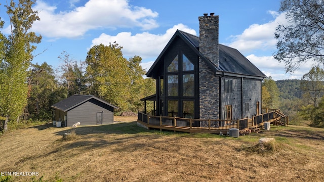 back of house with central air condition unit, a wooden deck, an outbuilding, a lawn, and a garage