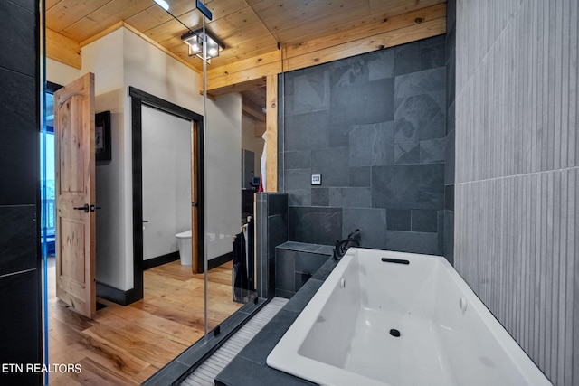 bathroom featuring wood-type flooring, a bathing tub, wooden ceiling, tile walls, and toilet