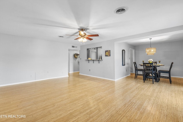 living room featuring light hardwood / wood-style floors and ceiling fan with notable chandelier