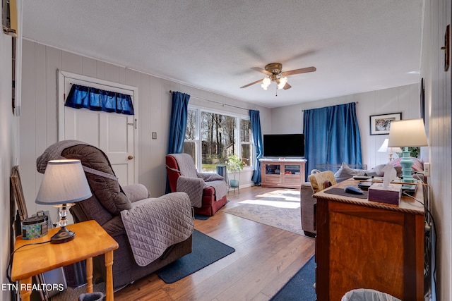 living room with wood-type flooring, a textured ceiling, and ceiling fan