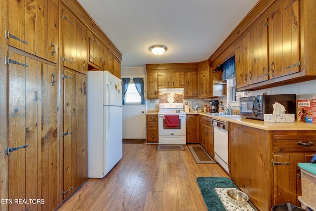 kitchen featuring sink, backsplash, light hardwood / wood-style floors, and white appliances