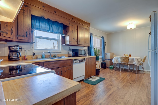 kitchen with ventilation hood, white appliances, sink, light hardwood / wood-style floors, and ornamental molding