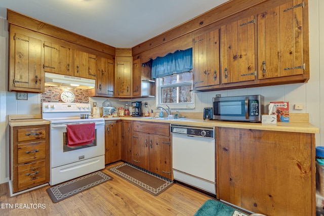 kitchen with decorative backsplash, white appliances, light hardwood / wood-style flooring, and sink