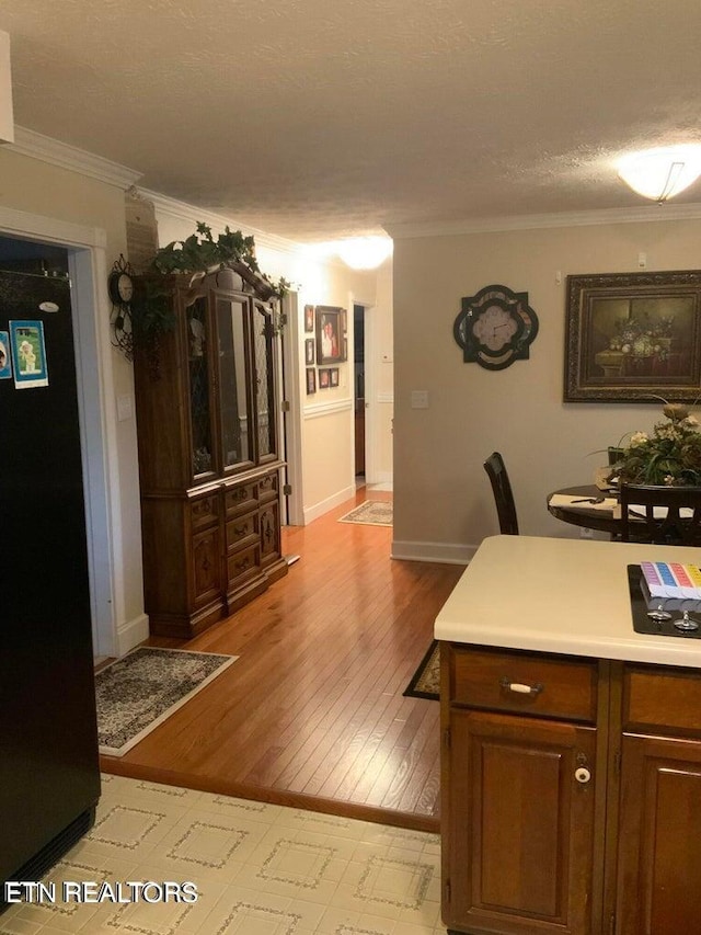 interior space featuring crown molding, light hardwood / wood-style floors, and a textured ceiling