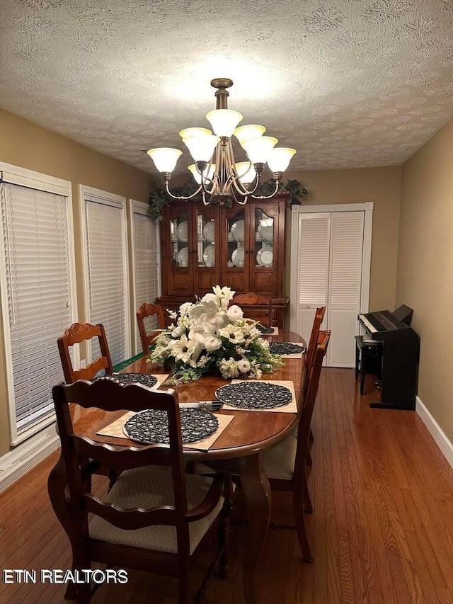 dining room with a textured ceiling, an inviting chandelier, and dark hardwood / wood-style flooring