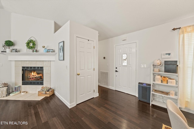 entryway with dark wood-type flooring and a fireplace