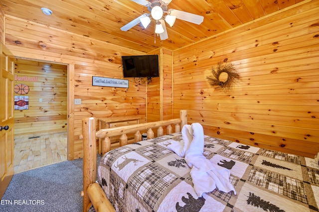 carpeted bedroom with wood walls, wooden ceiling, and ceiling fan