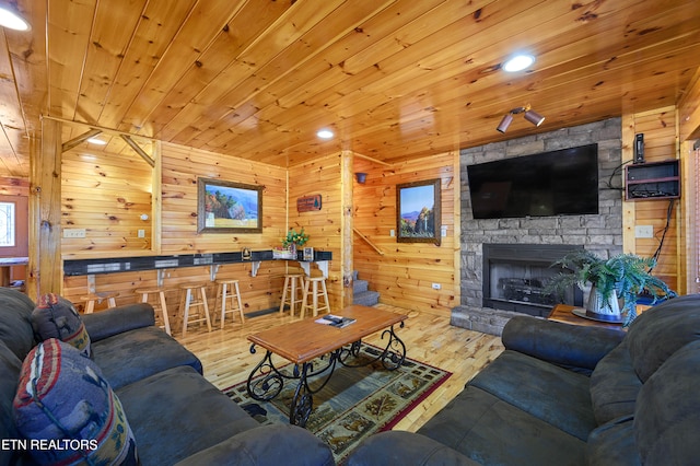 living room with wood walls, wood-type flooring, wood ceiling, and a fireplace