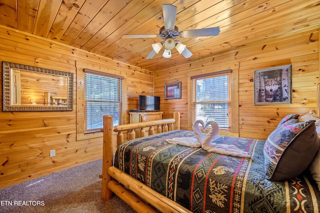 bedroom with ceiling fan, carpet floors, wooden walls, and multiple windows