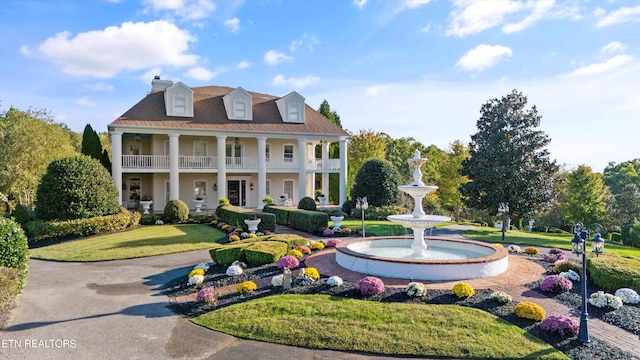 view of front of house with covered porch, a balcony, and a front lawn