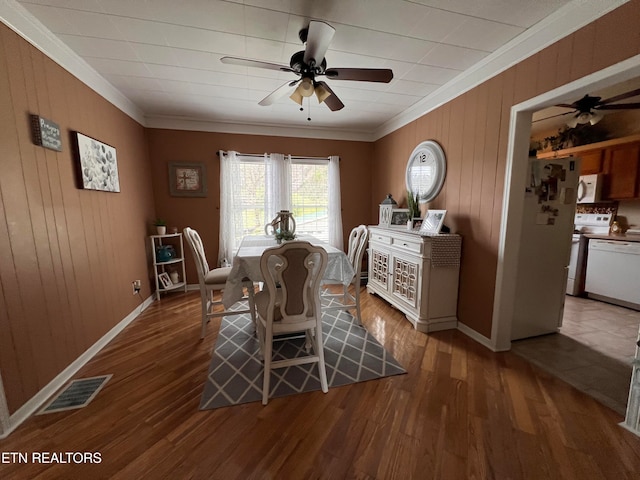 dining area featuring crown molding, hardwood / wood-style floors, and wooden walls