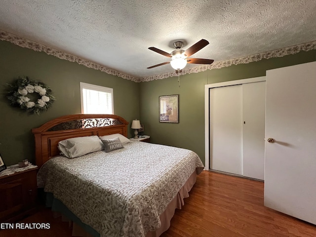 bedroom featuring ceiling fan, a closet, wood-type flooring, and a textured ceiling