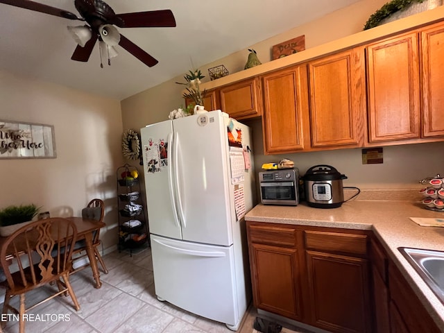 kitchen with light tile patterned floors, white refrigerator, and ceiling fan