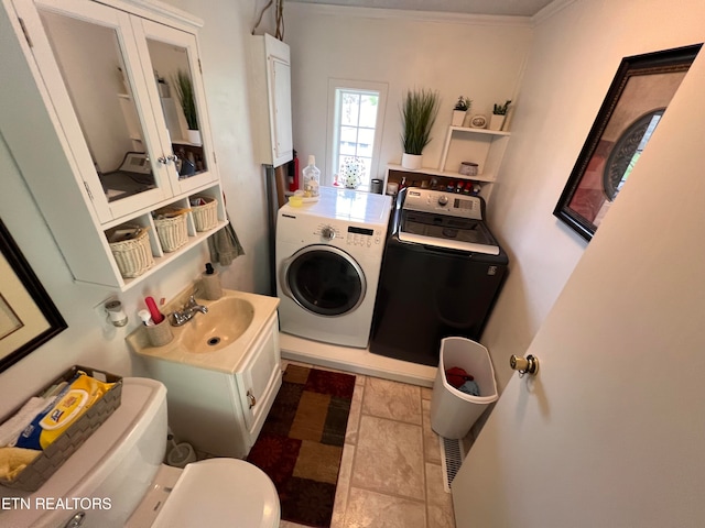 clothes washing area with separate washer and dryer, sink, and ornamental molding