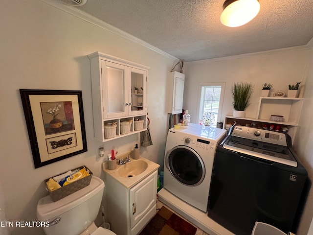 washroom featuring crown molding, sink, washer and dryer, and a textured ceiling