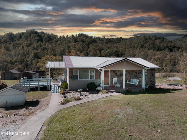 view of front of home with covered porch, a storage shed, and a lawn