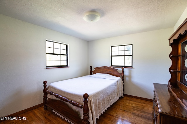 bedroom with dark wood-type flooring and a textured ceiling