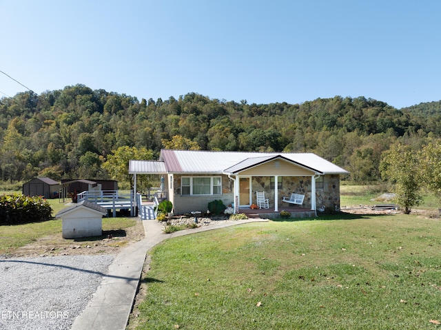 view of front of house with a porch, a front lawn, and an outbuilding