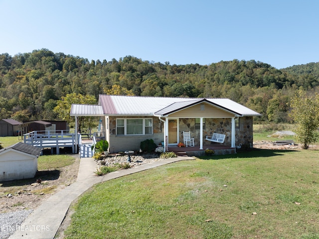 view of front of property with a porch, a front yard, and a storage shed