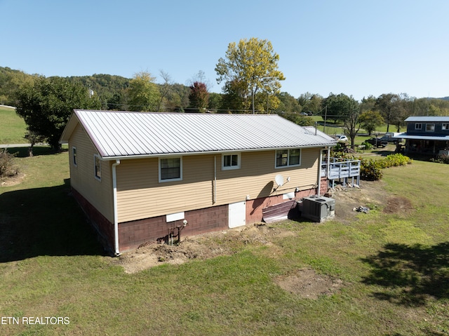 back of property featuring central AC and a lawn