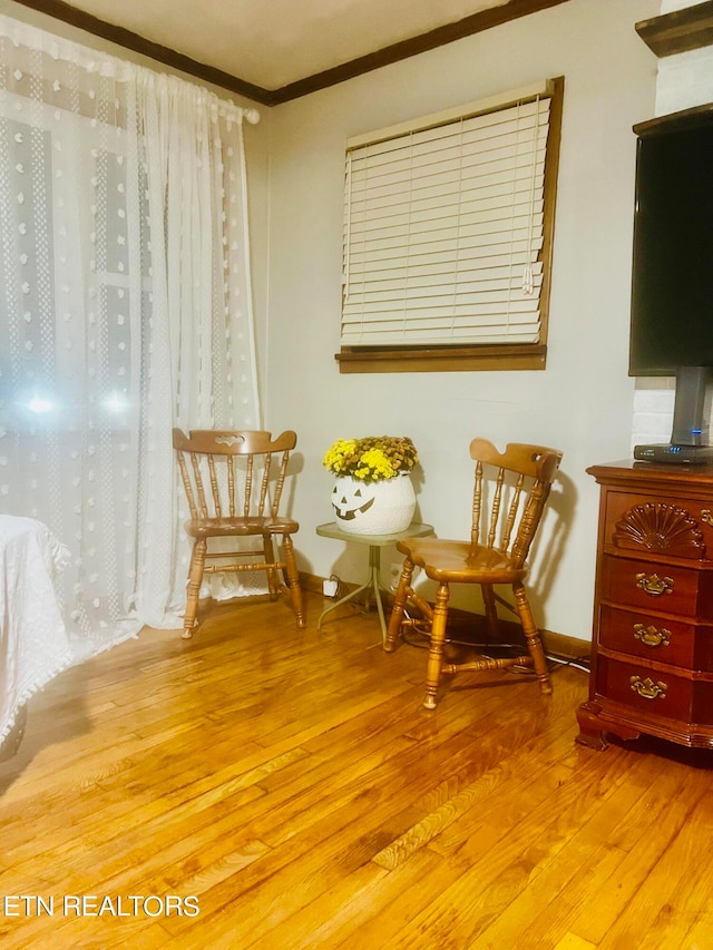 living area featuring ornamental molding and light hardwood / wood-style floors