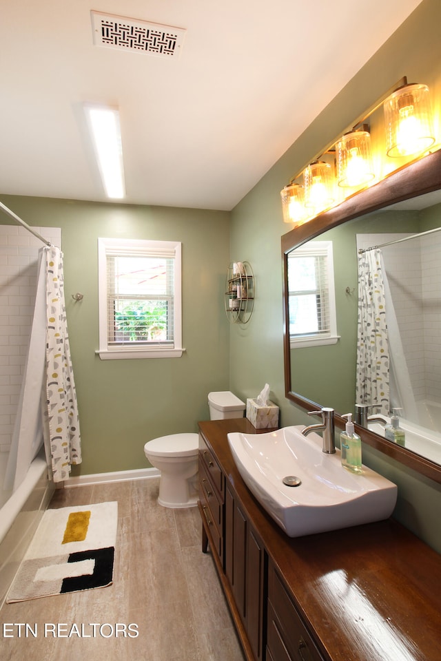 full bathroom featuring toilet, hardwood / wood-style flooring, vanity, and a healthy amount of sunlight