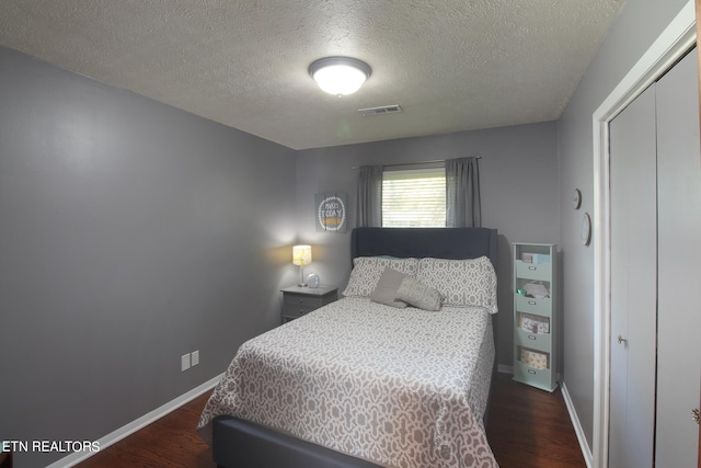 bedroom featuring a closet, dark hardwood / wood-style floors, and a textured ceiling