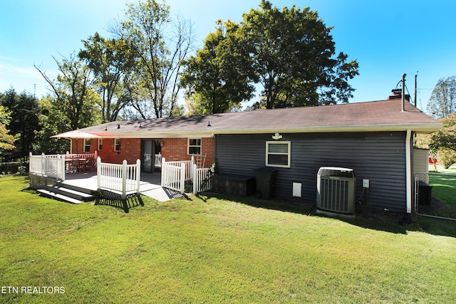 rear view of house featuring central AC unit, a wooden deck, and a yard